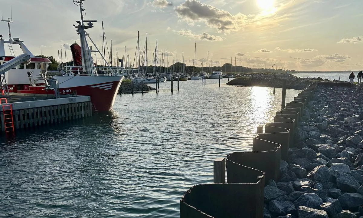 Aarøsund Lystbådehavn Amba: {"base": "no", "no": "Innl\u00f8pet sett utenifra. Kan oppleves litt vanskelig siden man \u00absl\u00e5ss\u00bb med str\u00f8mmen p\u00e5 utsiden for s\u00e5 \u00e5 komme inn en trang inngang.", "se": "Inloppet sett utifr\u00e5n. Kan upplevas lite sv\u00e5rt eftersom man 'sl\u00e5ss' med str\u00f6mmen p\u00e5 utsidan f\u00f6r att sedan komma in genom en tr\u00e5ng ing\u00e5ng.", "en": "The inlet seen from the outside. It can feel a bit challenging since you 'battle' against the current on the outside before entering a narrow passage.", "da": "Indl\u00f8bet set udefra. Kan opleves lidt vanskeligt, da man \u00abk\u00e6mper\u00bb med str\u00f8mmen p\u00e5 ydersiden for derefter at komme ind gennem en trang indgang.", "fr": "L'entr\u00e9e vue de l'ext\u00e9rieur. Peut \u00eatre un peu difficile car on \u00ab lutte \u00bb contre le courant \u00e0 l'ext\u00e9rieur avant d'entrer par une ouverture \u00e9troite.", "de": "Die Einfahrt von au\u00dfen gesehen. Kann etwas schwierig erscheinen, da man drau\u00dfen gegen die Str\u00f6mung \u00abk\u00e4mpft\u00bb und dann durch eine enge Einfahrt hineinkommt.", "es": "La entrada vista desde el exterior. Puede resultar un poco dif\u00edcil ya que uno \u00ablucha\u00bb con la corriente en el exterior antes de llegar a una entrada estrecha.", "it": "L'ingresso visto dall'esterno. Pu\u00f2 sembrare un po' complicato poich\u00e9 si \u00abcombatte\u00bb con la corrente all'esterno per poi entrare in un passaggio stretto.", "pt": "A entrada vista de fora. Pode parecer um pouco dif\u00edcil, pois voc\u00ea 'luta' contra a corrente do lado de fora para ent\u00e3o entrar por uma passagem estreita.", "nl": "De toegang vanaf buiten gezien. Kan een beetje moeilijk aanvoelen omdat je 'vecht' tegen de stroming aan de buitenkant en dan door een smalle ingang moet gaan.", "pl": "Wej\u015bcie ogl\u0105dane z zewn\u0105trz. Mo\u017ce by\u0107 nieco trudne, poniewa\u017c walczymy z pr\u0105dem na zewn\u0105trz, aby nast\u0119pnie wej\u015b\u0107 przez w\u0105skie wej\u015bcie.", "uk": "\u0412\u0445\u0456\u0434, \u043f\u043e\u0431\u0430\u0447\u0435\u043d\u0438\u0439 \u0437\u0437\u043e\u0432\u043d\u0456. \u041c\u043e\u0436\u0435 \u0432\u0456\u0434\u0447\u0443\u0432\u0430\u0442\u0438\u0441\u044f \u0442\u0440\u043e\u0445\u0438 \u0441\u043a\u043b\u0430\u0434\u043d\u0438\u043c, \u043e\u0441\u043a\u0456\u043b\u044c\u043a\u0438 \u0432\u0438 \u00ab\u0431\u043e\u0440\u0435\u0442\u0435\u0441\u044f\u00bb \u0437 \u0442\u0435\u0447\u0456\u0454\u044e \u0437\u043e\u0432\u043d\u0456, \u0449\u043e\u0431 \u0443\u0432\u0456\u0439\u0442\u0438 \u0447\u0435\u0440\u0435\u0437 \u0432\u0443\u0437\u044c\u043a\u0438\u0439 \u0432\u0445\u0456\u0434.", "ro": "Intrarea v\u0103zut\u0103 din exterior. Poate p\u0103rea pu\u021bin dificil deoarece \u00abte lup\u021bi\u00bb cu curentul din exterior pentru a intra \u00eentr-o intrare \u00eengust\u0103.", "tr": "Giri\u015fi d\u0131\u015far\u0131dan g\u00f6r\u00fcn\u00fcm. Ak\u0131nt\u0131yla 'm\u00fccadele' ederek dar bir giri\u015ften i\u00e7eri girmenin biraz zor olabilece\u011fi deneyimlenebilir.", "el": "\u0397 \u03b5\u03af\u03c3\u03bf\u03b4\u03bf\u03c2 \u03cc\u03c0\u03c9\u03c2 \u03c6\u03b1\u03af\u03bd\u03b5\u03c4\u03b1\u03b9 \u03b1\u03c0' \u03ad\u03be\u03c9. \u039c\u03c0\u03bf\u03c1\u03b5\u03af \u03bd\u03b1 \u03b8\u03b5\u03c9\u03c1\u03b7\u03b8\u03b5\u03af \u03bb\u03af\u03b3\u03bf \u03b4\u03cd\u03c3\u03ba\u03bf\u03bb\u03b7, \u03b1\u03c6\u03bf\u03cd \u00ab\u03c0\u03b1\u03bb\u03b5\u03cd\u03b5\u03c4\u03b5\u00bb \u03bc\u03b5 \u03c4\u03bf \u03c1\u03b5\u03cd\u03bc\u03b1 \u03ad\u03be\u03c9 \u03c0\u03c1\u03b9\u03bd \u03bc\u03c0\u03b5\u03af\u03c4\u03b5 \u03c3\u03b5 \u03bc\u03b9\u03b1 \u03c3\u03c4\u03b5\u03bd\u03ae \u03b5\u03af\u03c3\u03bf\u03b4\u03bf.", "cs": "Vjezd pohledem zven\u010d\u00ed. M\u016f\u017ee se jevit trochu obt\u00ed\u017en\u00fd, proto\u017ee se \u201ebojuje\u201c s proudem zven\u010d\u00ed, aby se pak vjelo \u00fazk\u00fdm vchodem.", "hu": "Bej\u00e1rat k\u00edv\u00fclr\u0151l n\u00e9zve. Kicsit neh\u00e9znek t\u0171nhet, mivel \u201ek\u00fcszk\u00f6d\u00fcnk\u201d az \u00e1ramlattal k\u00edv\u00fcl, majd be kell haj\u00f3zni egy sz\u0171k bej\u00e1raton.", "fi": "Sis\u00e4\u00e4nk\u00e4ynti ulkopuolelta n\u00e4htyn\u00e4. Voi tuntua hieman vaikealta, koska ulkopuolella 'taistelee' virtausta vastaan ja sitten saapuu kapeaan sis\u00e4\u00e4nk\u00e4yntiin.", "bg": "\u0412\u0445\u043e\u0434\u044a\u0442, \u0433\u043b\u0435\u0434\u0430\u043d \u043e\u0442\u0432\u044a\u043d. \u041c\u043e\u0436\u0435 \u0434\u0430 \u0441\u0435 \u043f\u043e\u0447\u0443\u0432\u0441\u0442\u0432\u0430 \u043c\u0430\u043b\u043a\u043e \u0442\u0440\u0443\u0434\u043d\u043e, \u0442\u044a\u0439 \u043a\u0430\u0442\u043e \u0441\u0435 \u201e\u0431\u043e\u0440\u0438\u0448\u201c \u0441 \u0442\u0435\u0447\u0435\u043d\u0438\u0435\u0442\u043e \u043e\u0442\u0432\u044a\u043d, \u043f\u0440\u0435\u0434\u0438 \u0434\u0430 \u0432\u043b\u0435\u0437\u0435\u0448 \u043f\u0440\u0435\u0437 \u0442\u0435\u0441\u0435\u043d \u043f\u0440\u043e\u0445\u043e\u0434.", "sr": "\u041f\u0440\u0438\u043b\u0430\u0437 \u0433\u043b\u0435\u0434\u0430\u043d\u043e \u0441\u043f\u043e\u0459\u0430. \u041c\u043e\u0436\u0435 \u0438\u0437\u0433\u043b\u0435\u0434\u0430\u0442\u0438 \u043c\u0430\u043b\u043e \u0442\u0435\u0448\u043a\u043e \u0458\u0435\u0440 \u0441\u0435 \u201e\u0431\u043e\u0440\u0438\u0442\u0435\u201c \u0441\u0430 \u0441\u0442\u0440\u0443\u0458\u043e\u043c \u043d\u0430\u043f\u043e\u0459\u0443, \u0434\u0430 \u0431\u0438 \u043f\u043e\u0442\u043e\u043c \u0443\u0448\u043b\u0438 \u0443 \u0443\u0441\u043a\u0438 \u0443\u043b\u0430\u0437.", "et": "Sadama suue v\u00e4ljastpoolt vaadatuna. V\u00f5ib tunduda veidi keeruline, kuna tuleb v\u00f5idelda v\u00e4ljas voolu vastu ja seej\u00e4rel siseneda kitsast sissep\u00e4\u00e4sust.", "lv": "Ieeja skat\u012bta no \u0101rpuses. Var b\u016bt nedaudz sare\u017e\u0123\u012bti, jo j\u0101c\u012bn\u0101s ar straumi \u0101rpus\u0113, lai iek\u013c\u016btu \u0161aur\u0101 ieej\u0101.", "lt": "\u012eplaukimas \u017ei\u016brint i\u0161 i\u0161or\u0117s. Gali b\u016bti \u0161iek tiek sunkus, nes reikia \u201ekovoti\u201c su srove i\u0161or\u0117je, kad patektum\u0117te \u012f siaur\u0105 \u012fplauk\u0105."}