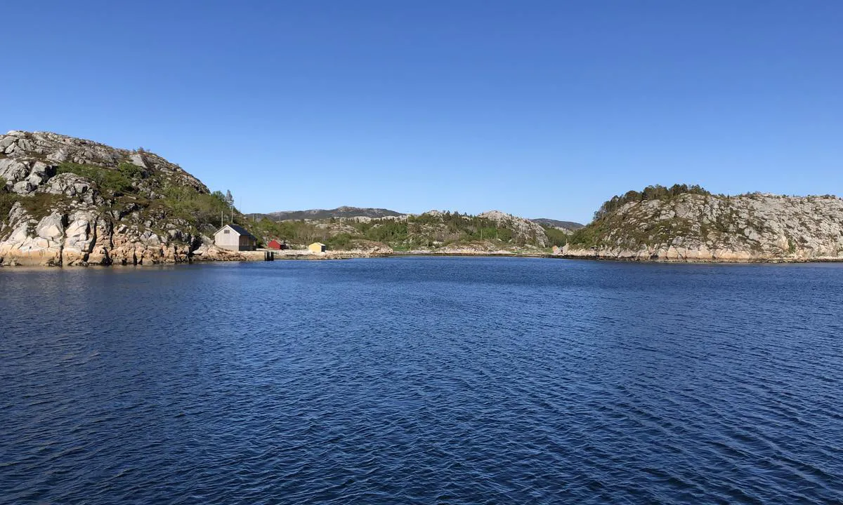 Enkel bebyggelse på land. Bildet er tatt østover fra bukta hvor man ankrer opp i Dalavågen.