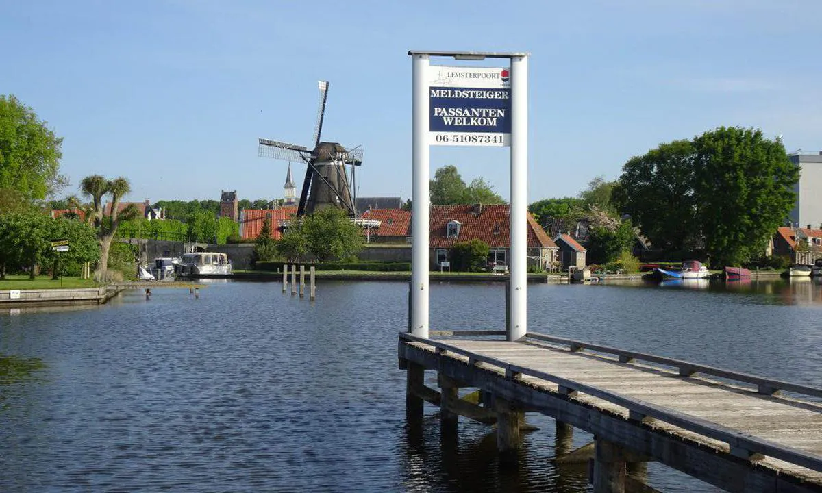 Jachthaven De Lemsterpoort (Sloten): Passersby welcome-jetty, next to the harbour-office. 
At the background the mill of beautiful and cosy Sloten, the smallest town of The Netherlands. 
(Photo from www.lemsterpoort.nl).