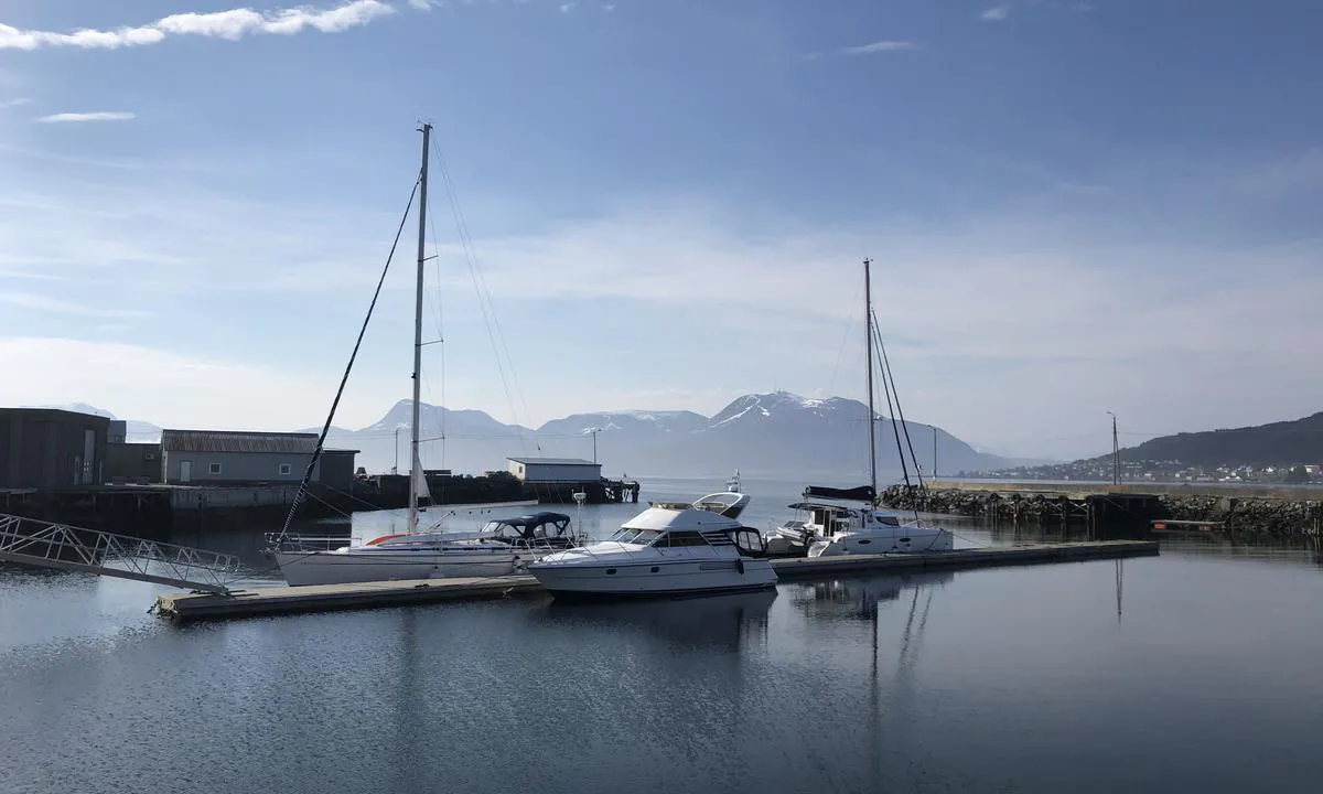 Flytebryggen i Longva Småbåtlag ligger rett inn i havna. Bildet er tatt fra landsiden. Når du ankommer havna seiler du inn i åpningen i moloen midt i bildet. Det er god plass til fire større båter på hver side av brygga. Den innerste siden av gjestebrygga (mot vest) kan være litt kronglete å navigere til i sterk vind. .