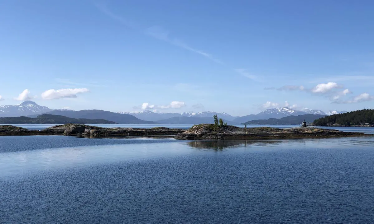 Rovikholmen ligger godt beskyttet innenfor flere øyer og her har du fantastisk utsikt mot fjellene på land. Bildet er tatt fra ankringsplassen mot sydvest.