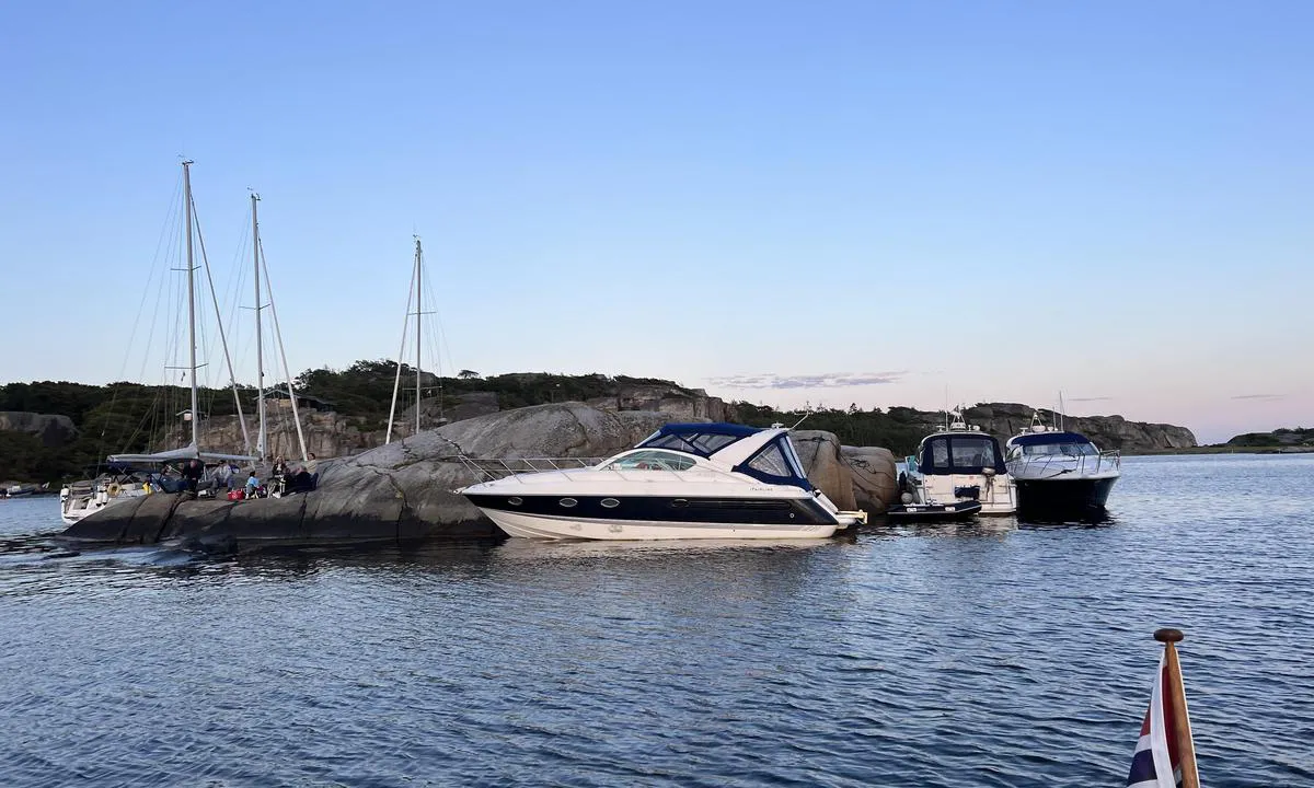 Sør i Ommane: Holmer i bukten. Fortøyning longside ved en av holmene. Bolter i fjellet. Også mulig med dregg ut. Jolletur over sundet til flott sandstrand. Flotte glattskurte svaberg.